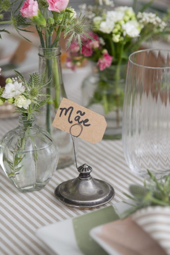 Foto aproximada com o marcador de lugar na mesa exibindo a etiqueta com a palavra "mãe". 