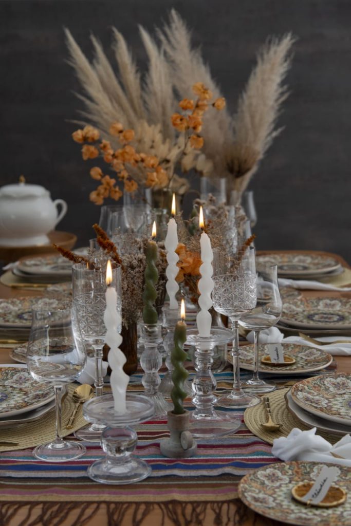 No centro da mesa de almoço marroquino, velas brancas torcidas e flores secas, criam um clima acolhedor.