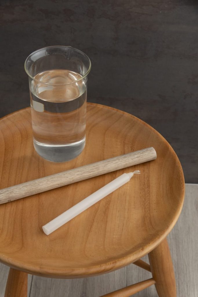 Material para fazer a vela torcida: vidro com água, bastão de madeira e vela branca