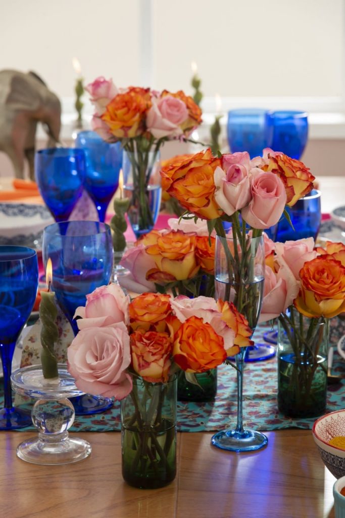 No centro da mesa, vários buquês de rosas em tom de rosa claro, e amarelo com as bordas em laranja