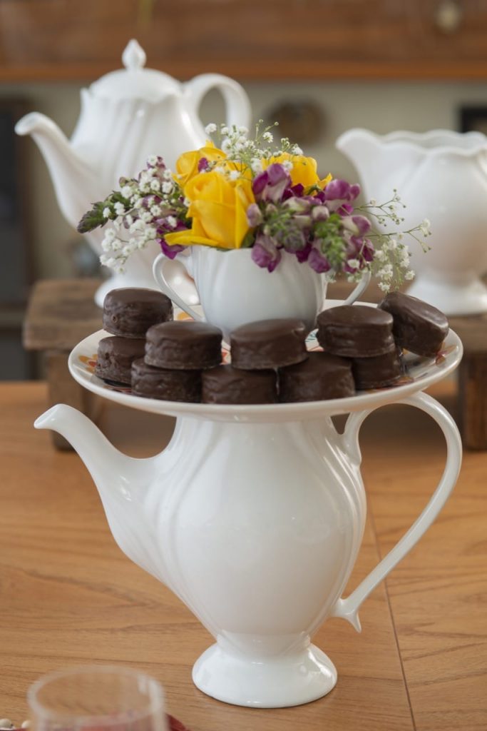 Bule branco com estilo romântico, prato com pães de mel e açucareiro com flores. 