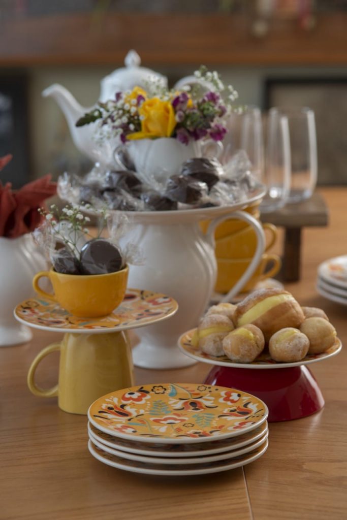 Louças em branco, amarelo e vermelho servem de base para pratos contendo doces.