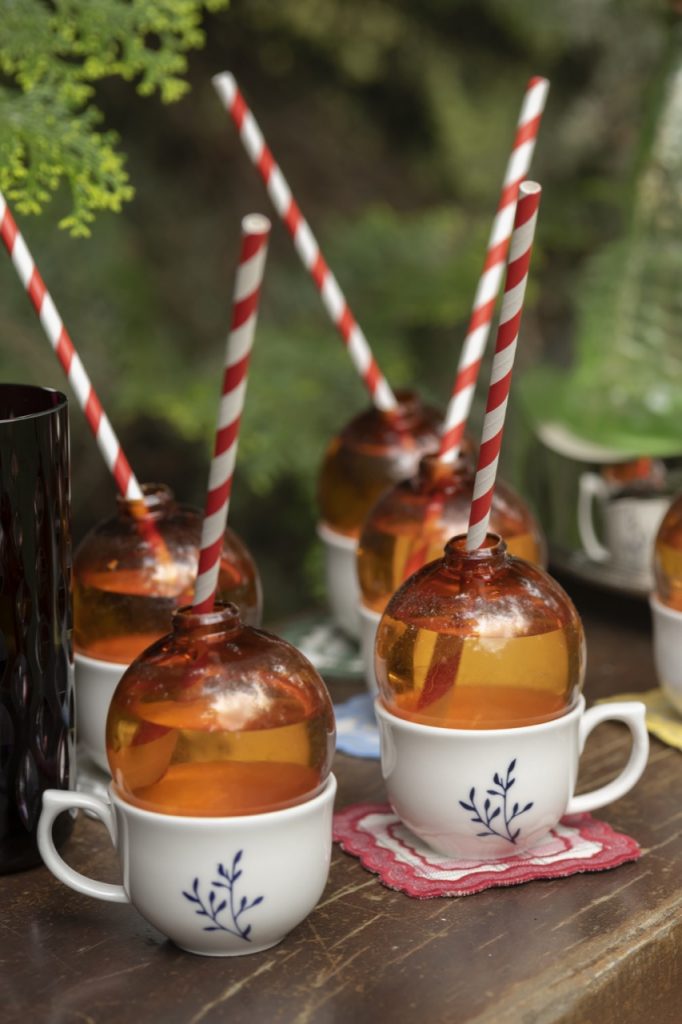 Seis bolas de natal dentro de xícaras, com canudinhos de papel. 