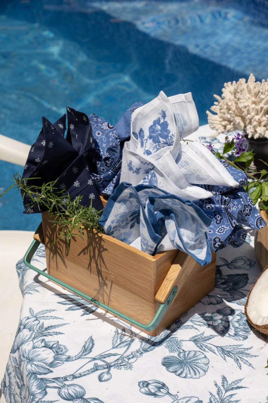 Porta-talheres de madeira contendo seis guardanapos de tecido, todos estampados em azul e branco. 