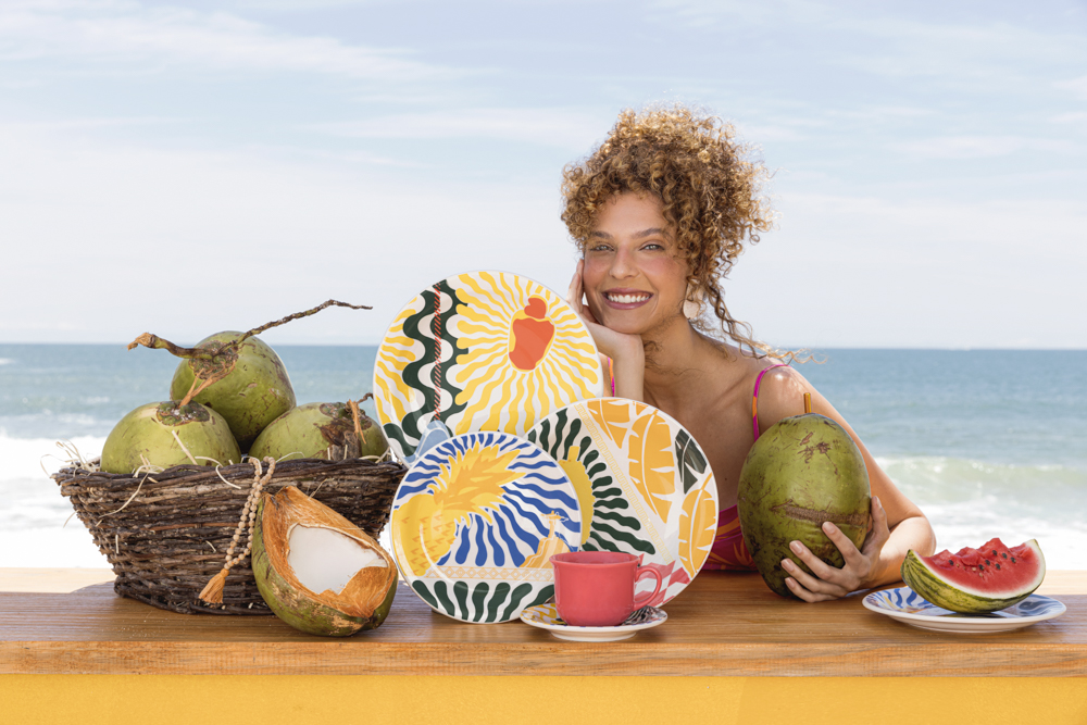 Imagem: menina na praia com louças e coco.