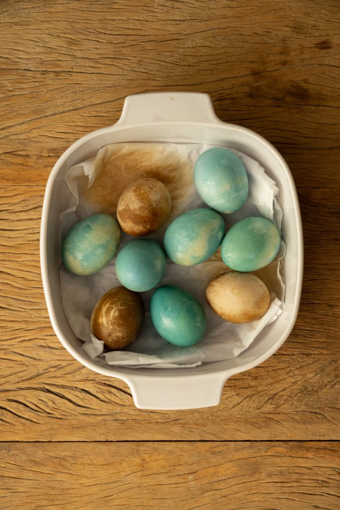 Imagem: ovos tingidos de azul e marrom em refratária branca.
