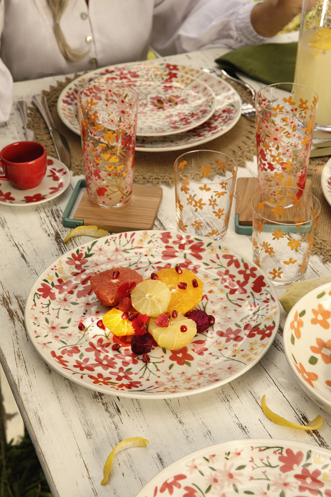 Imagem: porcelana floral e copos decorados com flores em mesa.