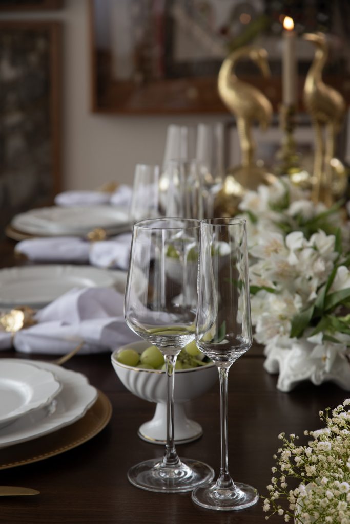 Foto da mesa posta com duas taças de cristal em destaque, para água e para espumante.
