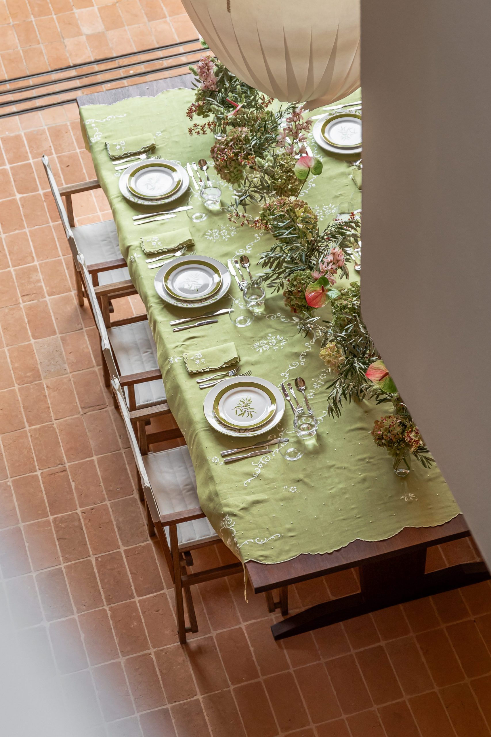 Imagem: mesa para o Dia das Mães com toalha verde, arranjos de folhas e porcelanas Oxford decoradas com folhas de Oliveiras. 