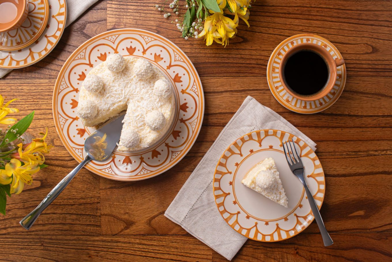Imagem: pratos com estampa em aquarela amarela servidos com torta de coco e café preto, sobremesa de dia das mães. Linha Unni Nuray da Oxford. 