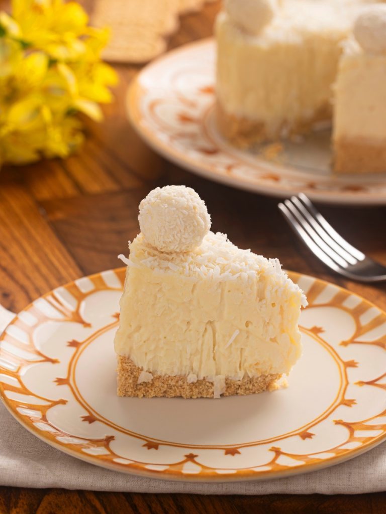 Imagem: prato com estampa em aquarela amarela servido com torta de coco. Linha Unni Nuray da Oxford. 