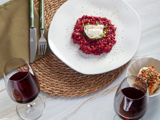 Imagem: risoto de beterraba na cor vermelha servido em prato branco de formato orgânico da linha Ryo White da Oxford. Receita para o Dia dos Namorados.